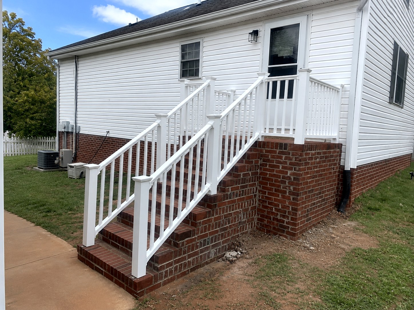 Brick staircase with white railings and brick foundation wainscot