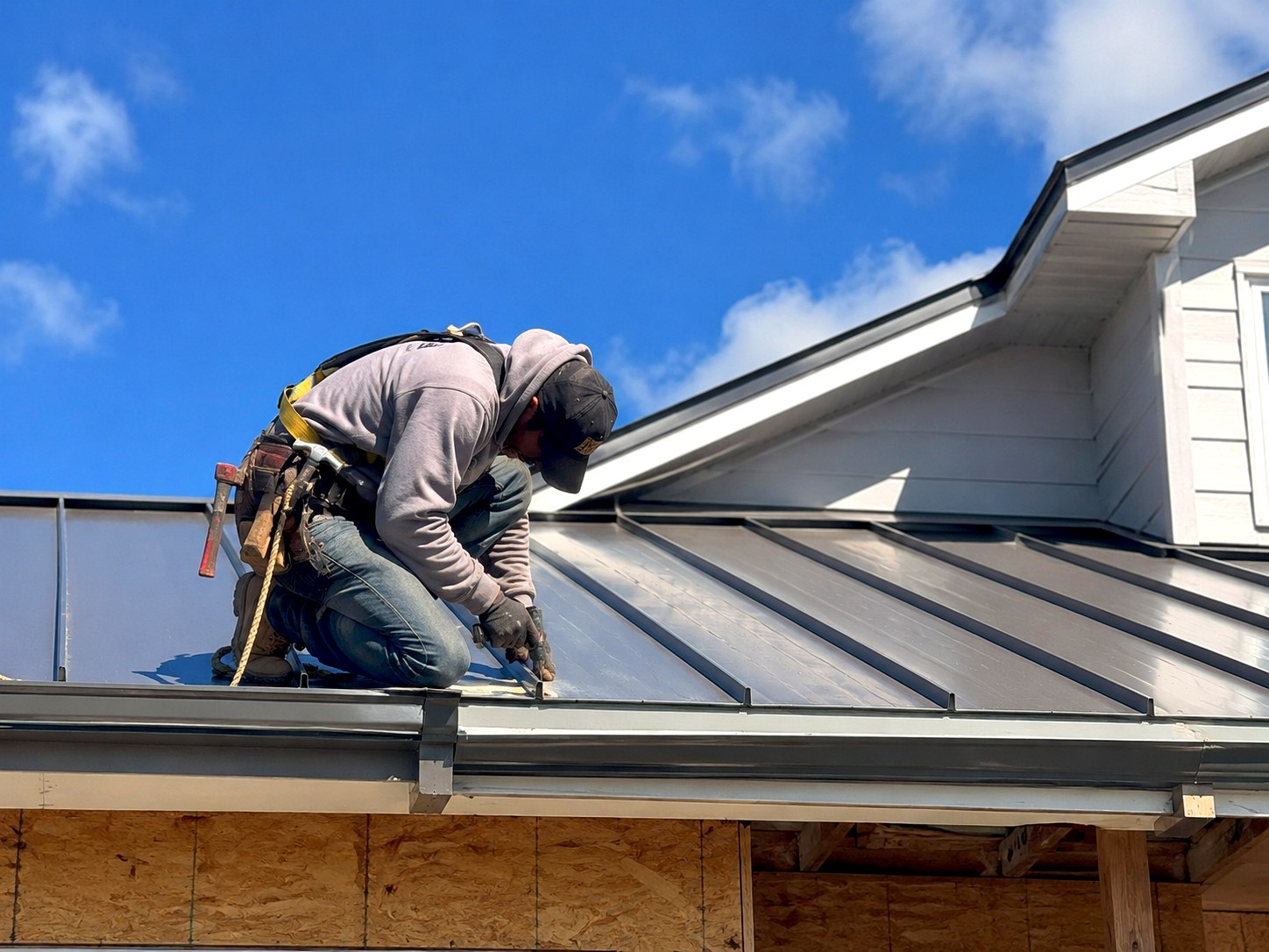 Contractor installing a standing seam metal roof on a residential home